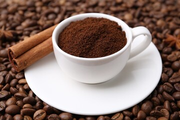 Cup with instant coffee powder and cinnamon on beans, closeup