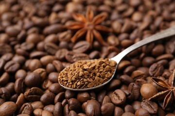 Spoon with granulated instant coffee and star anise on beans, closeup