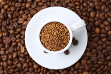 Cup with granulated instant coffee on beans, top view