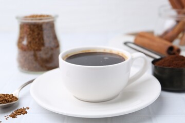 Cup of aromatic coffee and granulated instant coffee on white table, closeup