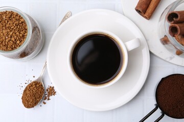 Cup of aromatic coffee and instant powder on white table, flat lay