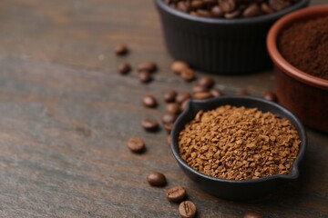 Different types of instant coffee and beans in bowls on wooden table, closeup. Space for text