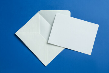Blank invitation card and envelope on blue background, flat lay. Space for design