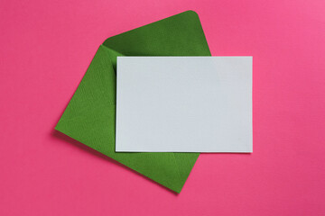 Blank invitation card and envelope on pink background, top view. Space for design