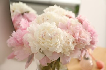 Beautiful peonies in vase on wooden vanity indoors, closeup