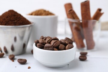 Roasted beans, different types of instant coffee and cinnamon sticks on light table, closeup
