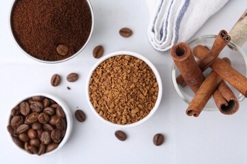 Different types of instant coffee, beans and cinnamon sticks on light table, flat lay