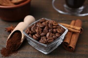 Roasted beans, instant coffee powder and cinnamon sticks on wooden table, closeup