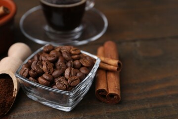 Roasted beans, instant coffee powder and cinnamon sticks on wooden table, closeup