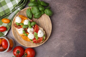 Tasty sandwich with mozzarella cheese, tomatoes and basil on brown table, flat lay. Space for text