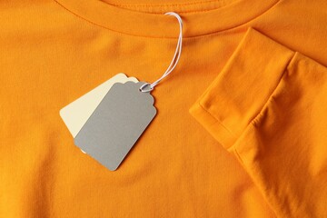 Cardboard tags on orange garment, top view