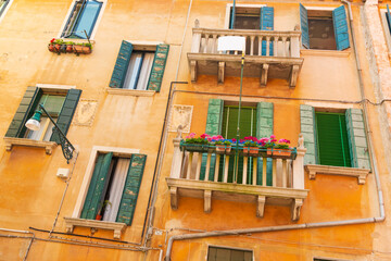 Typical Venetian ochre stucco house with uneven windows with colorful wooden shutters, Venice, Italy