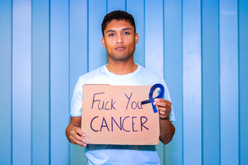 Man holding sign with cancer awareness ribbon and strong anti-cancer message