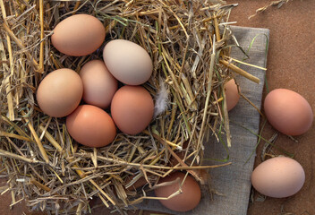 Farm brown eggs in nest straw. Rustic flat lay, top view