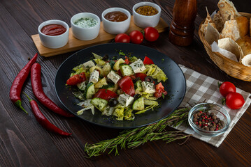 Greek salad with sauces on a wooden background