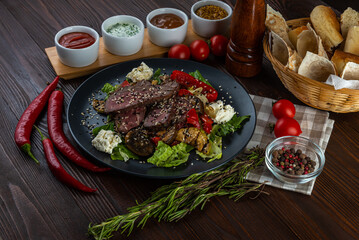 Warm salad with duck and sauces on wooden background