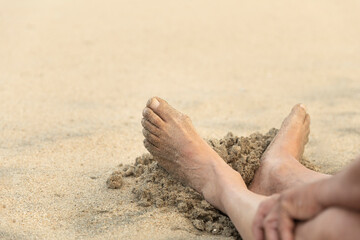 Retired mature old man enjoying the summer vacation alone at the beach sitting in the sand. Freedom concept.