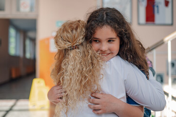 Two schoolgirls hugging in school hallway, showing friendship and support