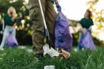 Group of people picking up trash in park with grabber tool