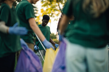 Group of volunteers cleaning park picking up trash in bags