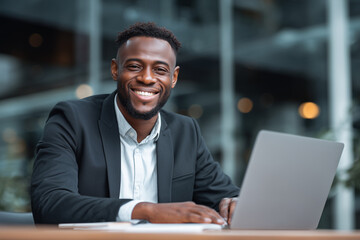 Fototapeta premium Smiling businessman at desk with laptop