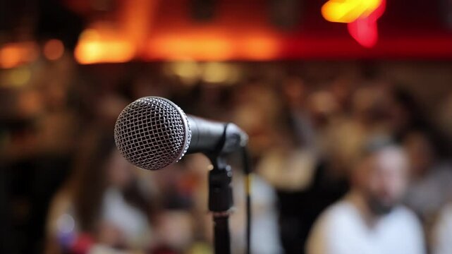 Close-up of microphone on stage with blurred audience background, Event setup for public speaking, conference or performance in warm ambient lighting