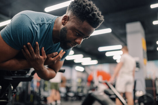 Young athlete experiencing chest pain in gym after intense workout