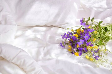 A bouquet of wild flowers in the bedroom on the bed in the morning.