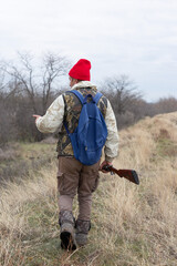Mature hunter man holding a shotgun and walking through a field