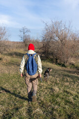 Mature hunter man holding a shotgun and walking through a field