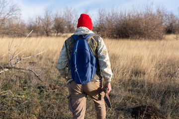 Mature hunter man holding a shotgun and walking through a field
