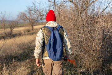 Mature hunter man holding a shotgun and walking through a field