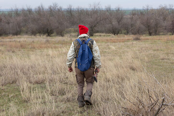 Mature hunter man holding a shotgun and walking through a field