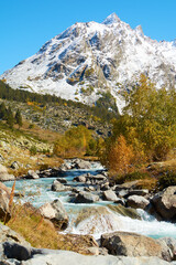 Beautiful mountain scenery. River, valley, snow, blue sky, white clouds.