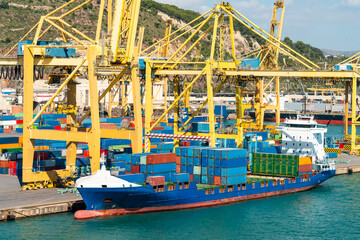 Cargo ship docked at container terminal with yellow cranes