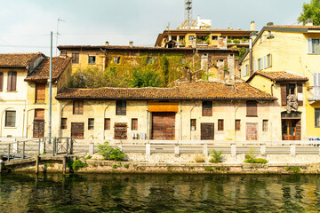 Old rustic house with tiled roof by canal, Navigli district, Milan