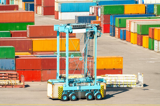 Container handler vehicle in cargo terminal with stacked multicolored cargo containers