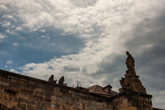 Fototapeta Baroque statues on Charles Bridge in Prague silhouetted against dramatic cloudy sky. A moody scene from the historic heart of the Czech capital