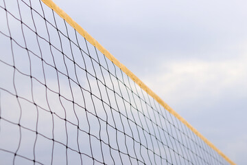 Beach volleyball net close-up. Volleyball net fragment on the beach against the sky. Sport, beach volleyball. Active recreation concept. Background. Yellow net detail. Sports ground