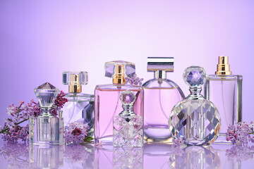 Bottles of perfume and lilac flowers on mirror surface against violet gradient background