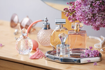 Bottles of perfumes, accessories and lilac flowers on wooden table