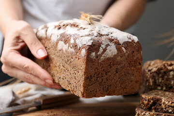 Woman with freshly baked bread at table against grey background, closeup