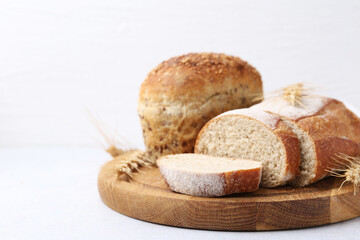 Freshly baked loaves of bread and spikes on light table, closeup. Space for text
