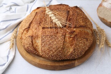 Freshly baked bread with sesame seeds and spikes on light grey table, closeup