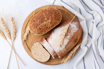 Freshly baked loaves of bread and spikes on light table, flat lay