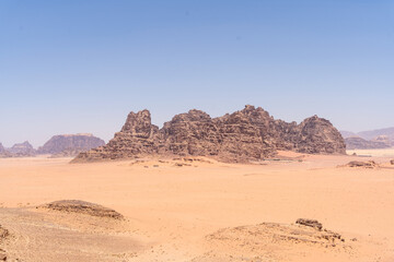 Fototapeta na wymiar Desert Majesty: Witness the raw beauty of a vast desert landscape under a clear blue sky. The towering rock formations and endless dunes evoke a sense of wonder and tranquility.