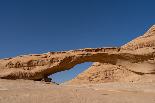 Desert Arch: Capturing the raw beauty of nature, a sandstone arch majestically frames the clear blue sky, evoking a sense of wonder and timelessness in the vast desert landscape.