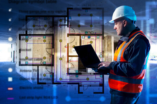 Engineer in safety gear reviews electrical wiring plan on laptop at construction site, interior blueprint with lighting and socket layout &mdash; Electrical engineering, construction.