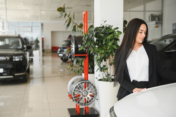 Saleswoman showing a new car in a dealership