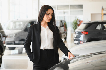 woman touching car hood in dealership showroom